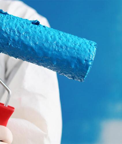 Spécialiste du bâtiment en blouse blanche tenant un pinceau dans la main