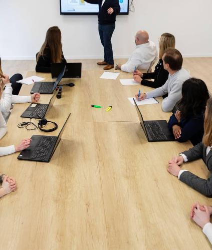 Table avec des hommes et des femmes en réunion autour d'un présentateur