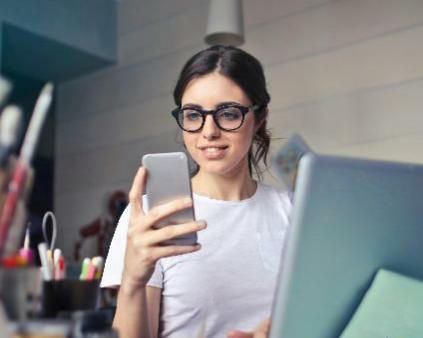 Une femme tenant un téléphone entouré par des pinceaux pour illustrer l'expertise d'accompagnement de Cerfrance dans les métiers pour les particuliers