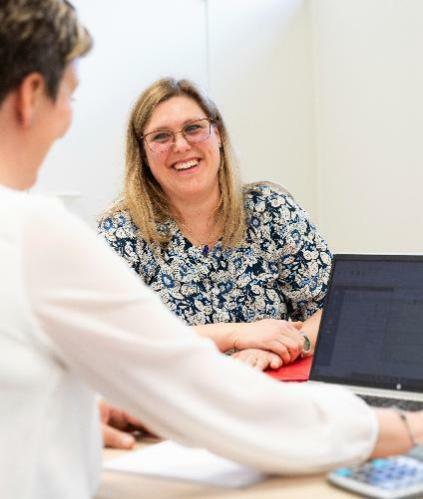 Une collaboratrice de Cerfrance avec une cliente autour d'une table souriante avec des papiers