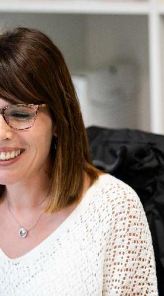 Expertise en management en ressources humaines, Cerfrance vous accompagne, une RH Cerfrance souriante devant son ordinateur avec une doudoune logoté sur sa chaise