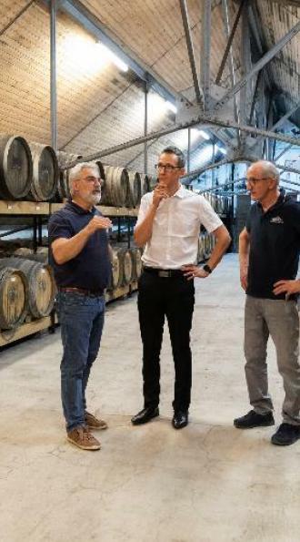 Un conseiller patrimonial chez un client-adhérent Cerfrance dans une cave avec des tonneaux