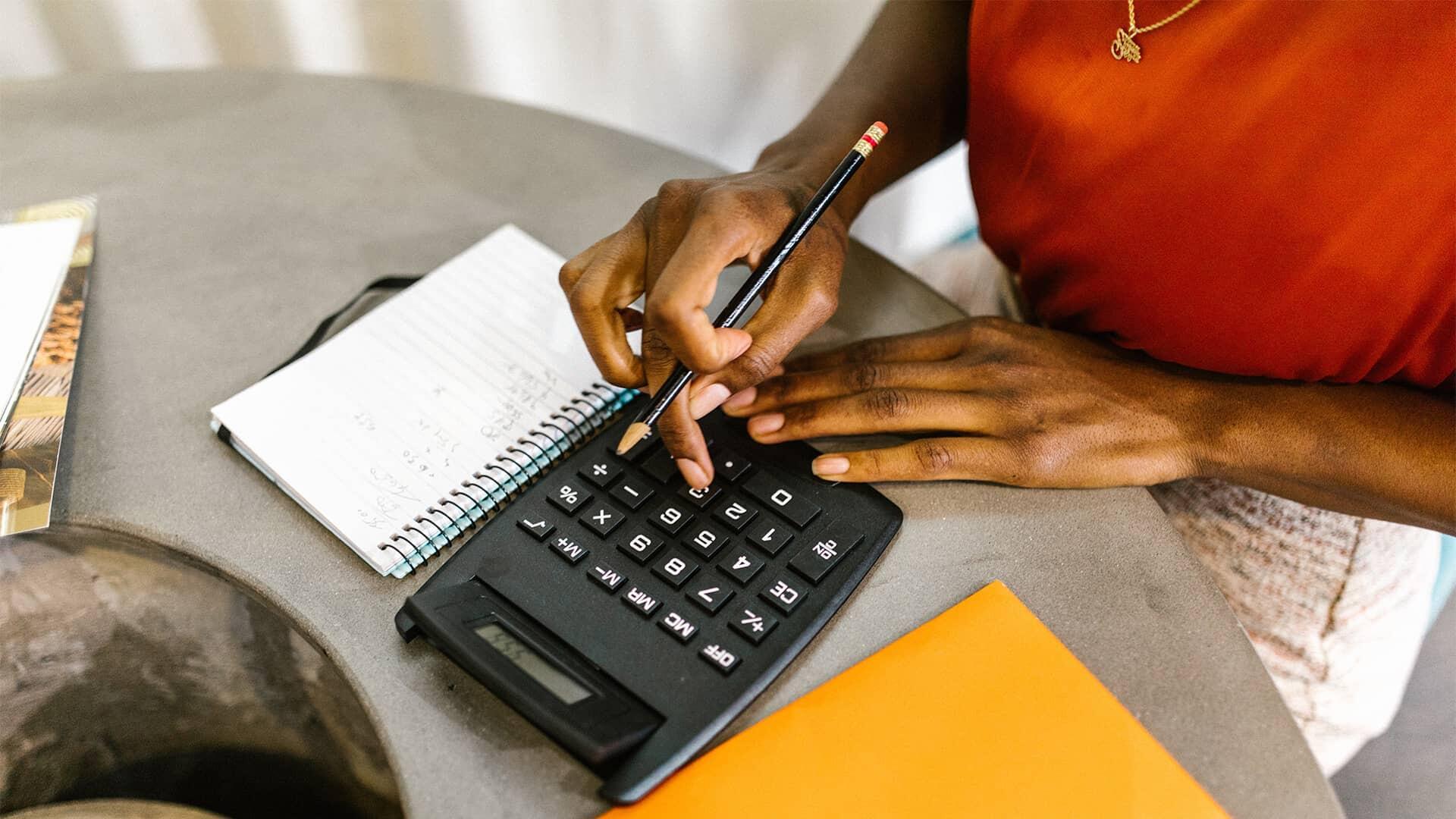 Femme sur une calculatrice en train d'élaborer un budget