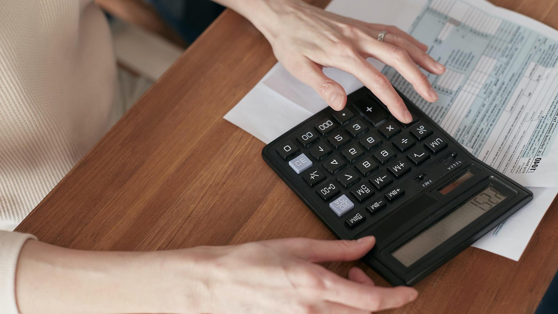 Femme devant une fiche de paie avec une calculatrice sous la main pour illustrer l'importance des rémunérations périphériques