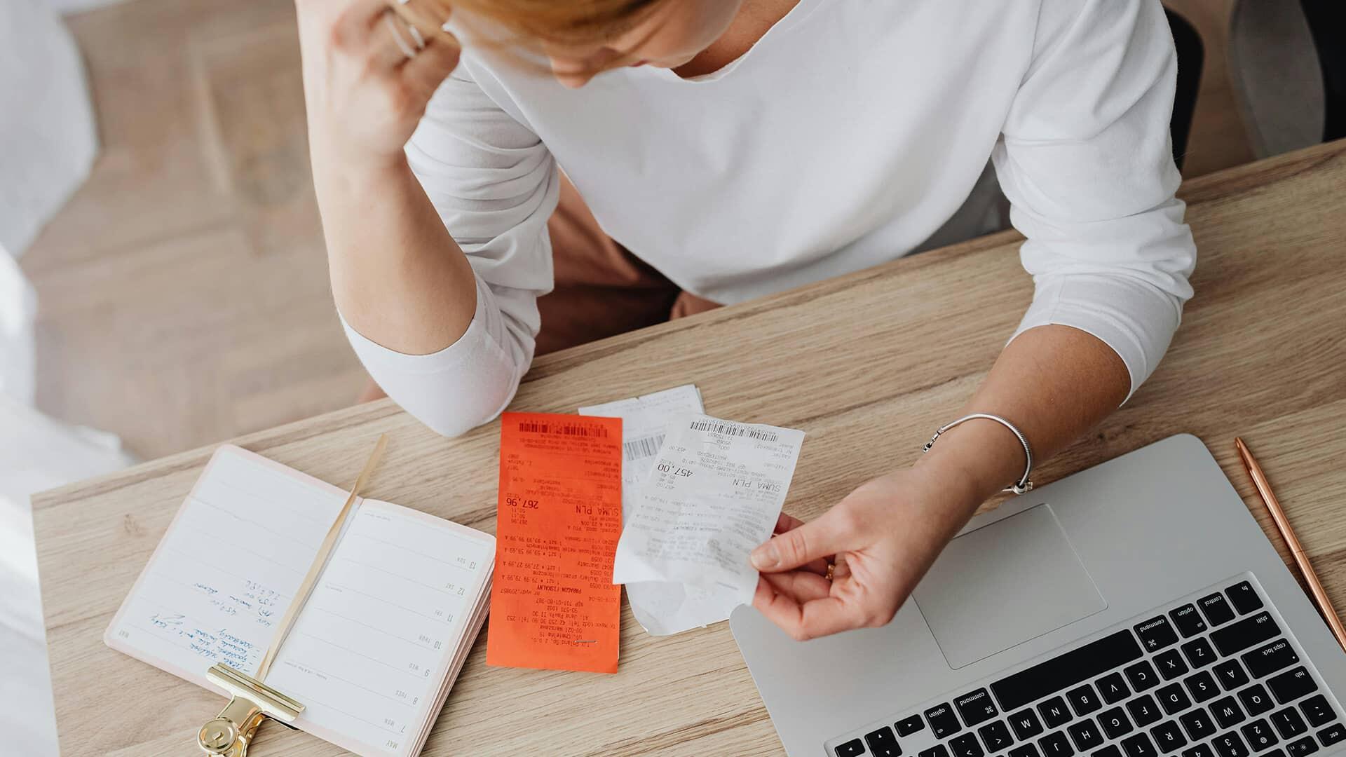 Femme la tete dans la main avec des facture sous les yeux pour illustrer dépense et charge