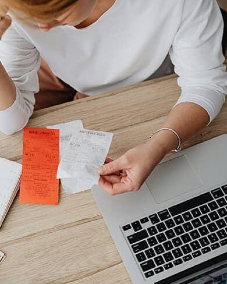 Femme la tete dans la main avec des facture sous les yeux pour illustrer dépense et charge