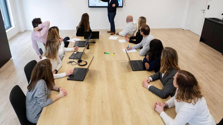 Table avec des hommes et des femmes en réunion autour d'un présentateur