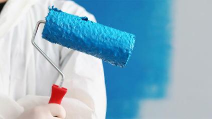 Spécialiste du bâtiment en blouse blanche tenant un pinceau dans la main